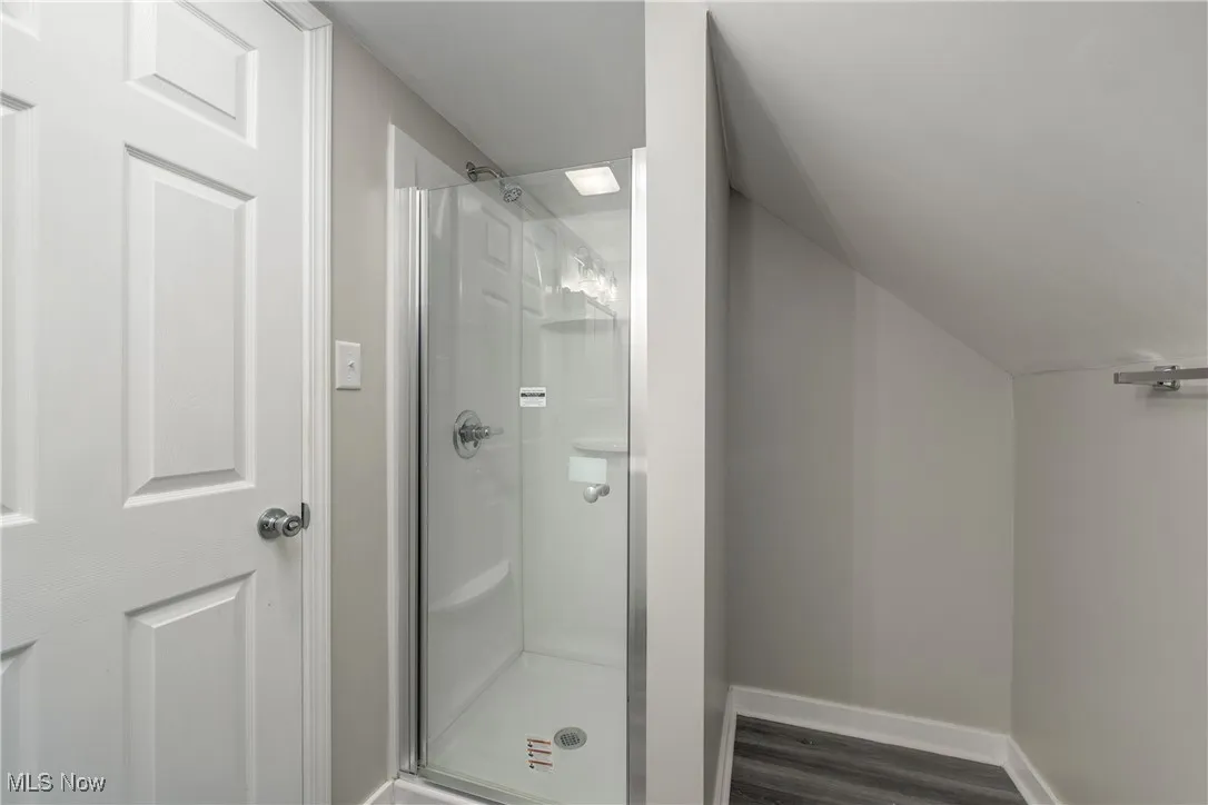 Bathroom with a shower stall and dark wood-style floors