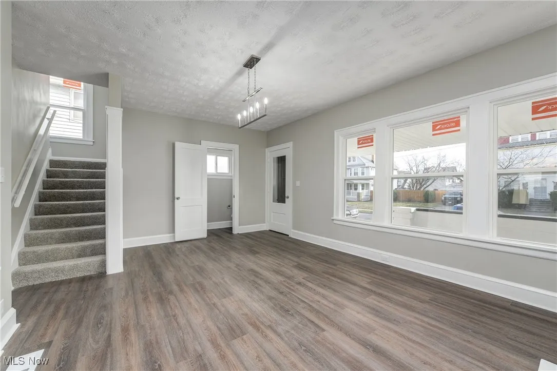 Unfurnished living room with stairway, dark wood-style floors, and a textured ceiling