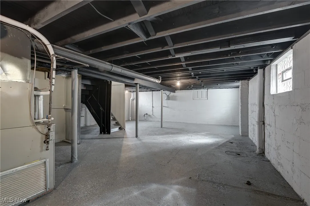 Below grade area with heating unit and stairway
