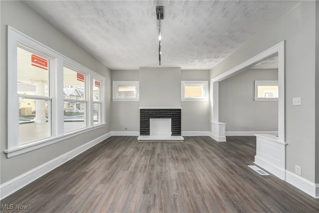 Unfurnished living room featuring dark wood finished floors, a fireplace, and a textured ceiling