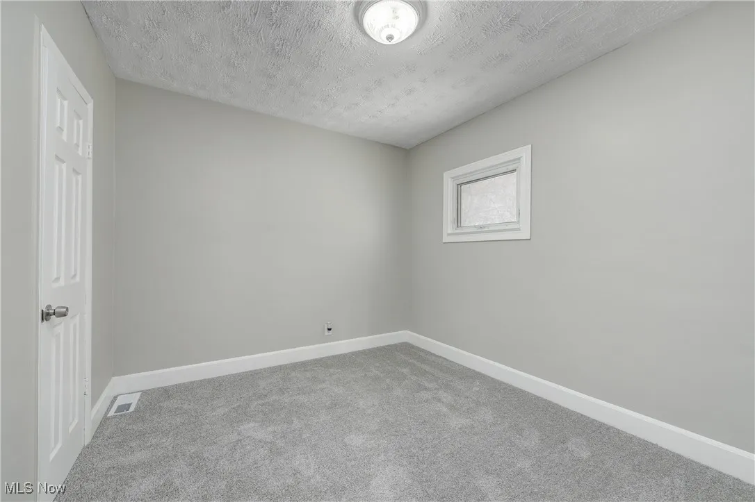Unfurnished room featuring carpet and a textured ceiling