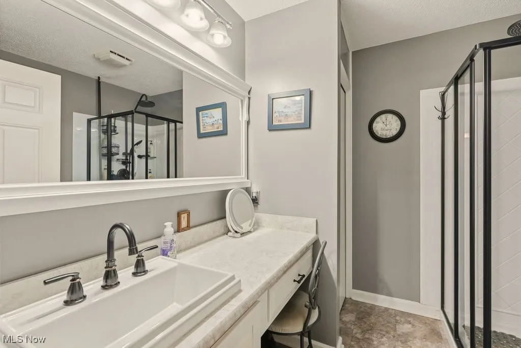 Bathroom with vanity, a stall shower, and a textured ceiling