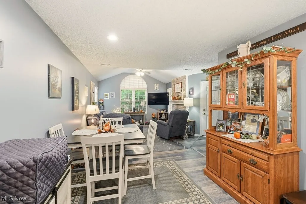 Dining space featuring vaulted ceiling, wood finished floors, ceiling fan, and a textured ceiling