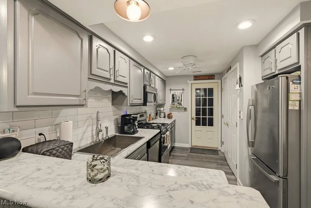 Kitchen featuring stainless steel appliances, backsplash, recessed lighting, ceiling fan, and dark wood-style floors