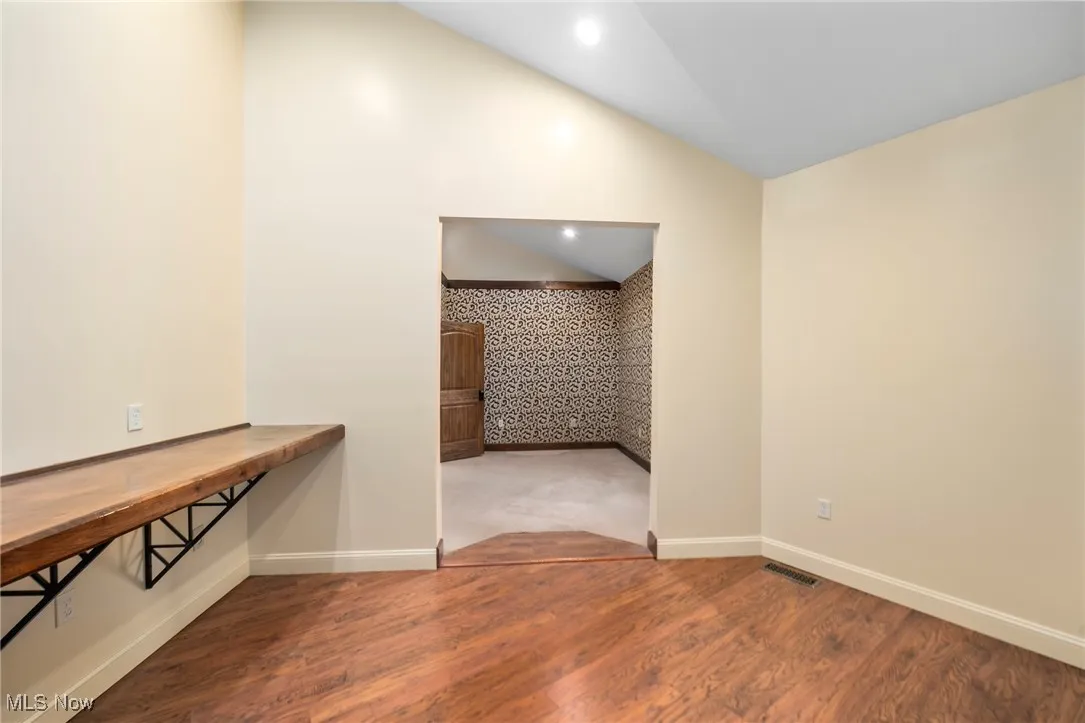 Spare room with lofted ceiling, wood finished floors, and recessed lighting