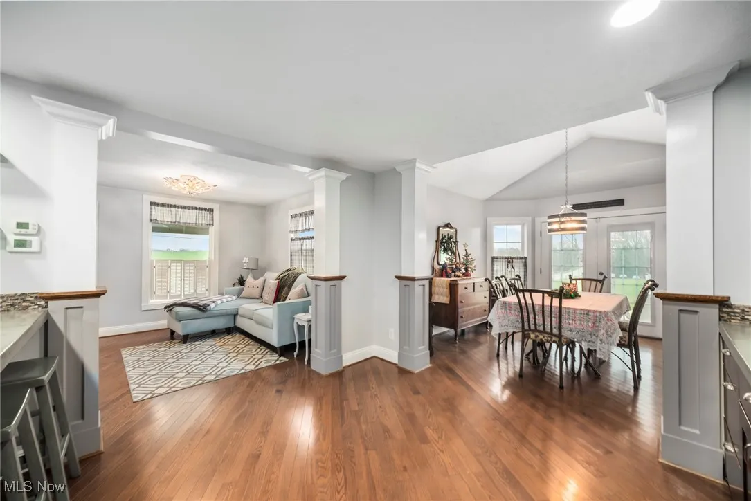 Dining area with lofted ceiling, dark wood-style flooring, healthy amount of natural light, and decorative columns