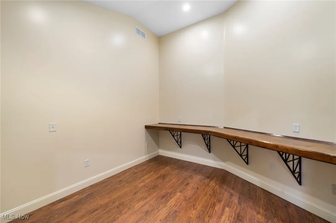 Unfurnished office with baseboards and dark wood-type flooring