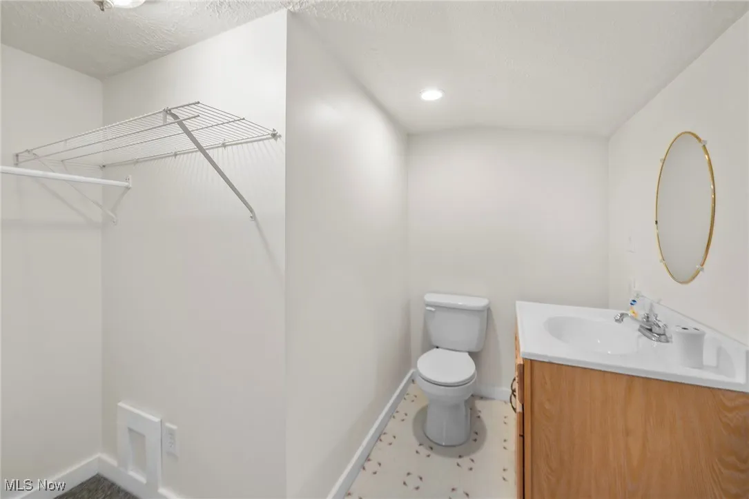 Bathroom with vanity, a textured ceiling, and a walk in closet