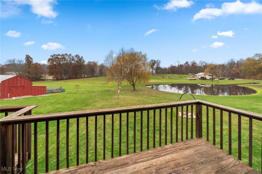Deck featuring a water view, an outdoor structure, a lawn, and a barn