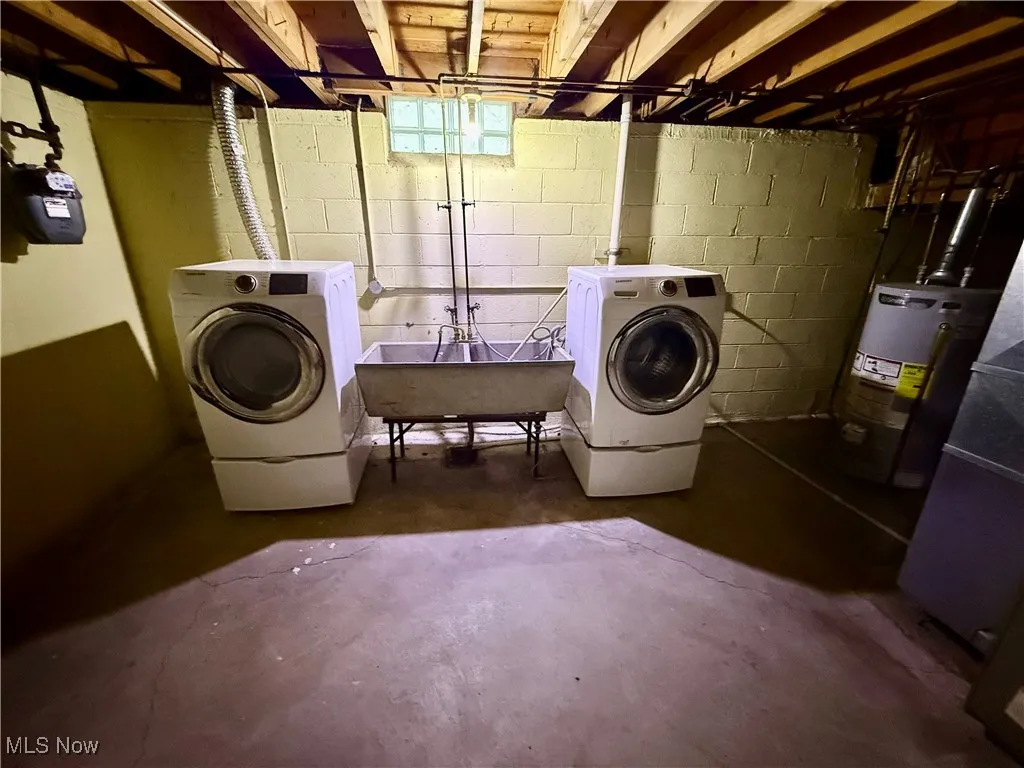 Washroom with concrete flooring, gas water heater, and separate washer and dryer