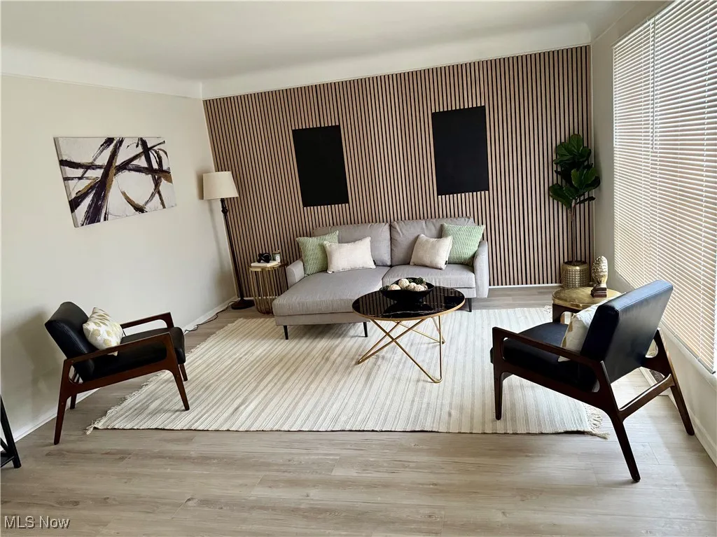 Living room featuring an accent wall and light wood-style flooring