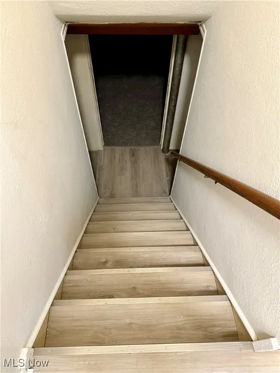Staircase featuring a textured wall and hardwood / wood-style floors