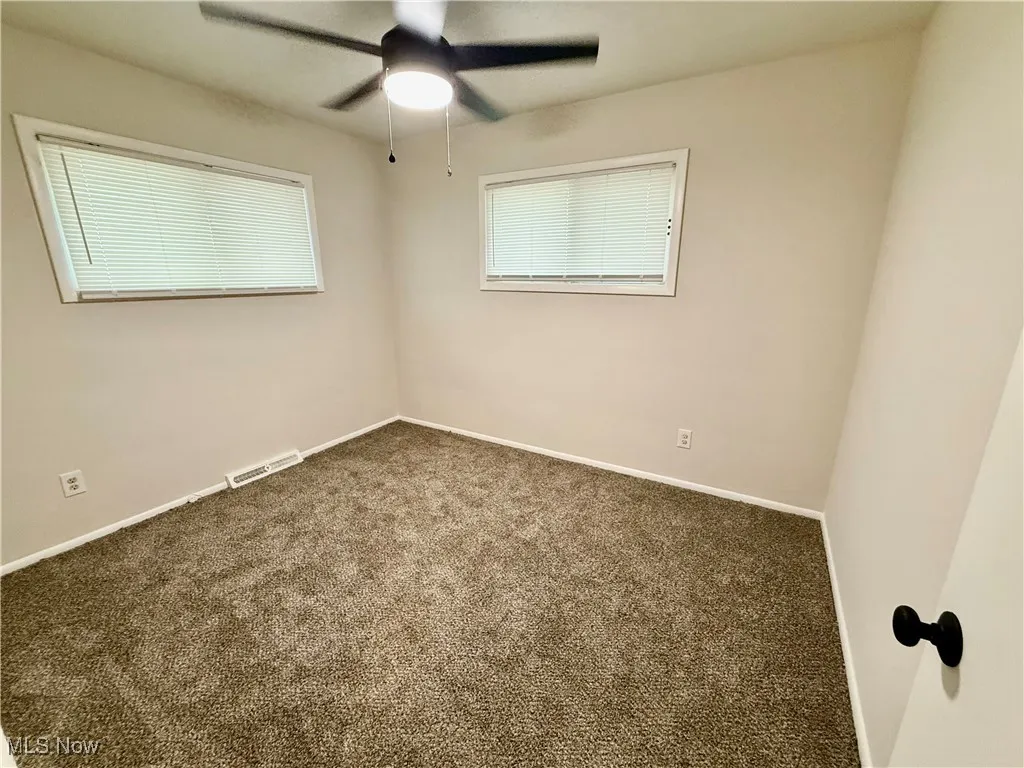 Empty room with carpet and a ceiling fan