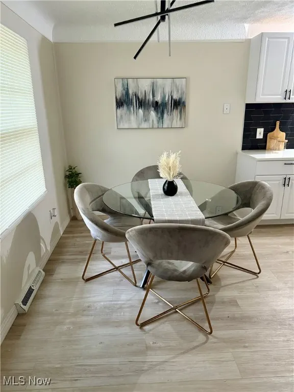 Dining space with a textured ceiling and light wood finished floors