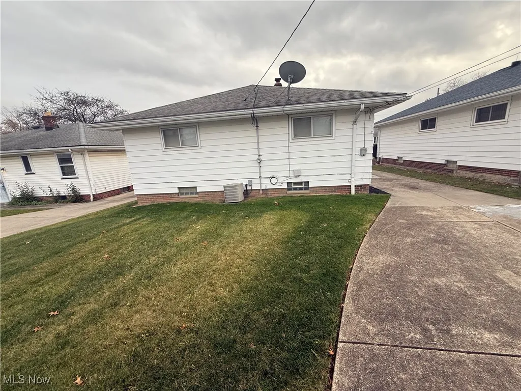 Back of house with a yard and roof with shingles