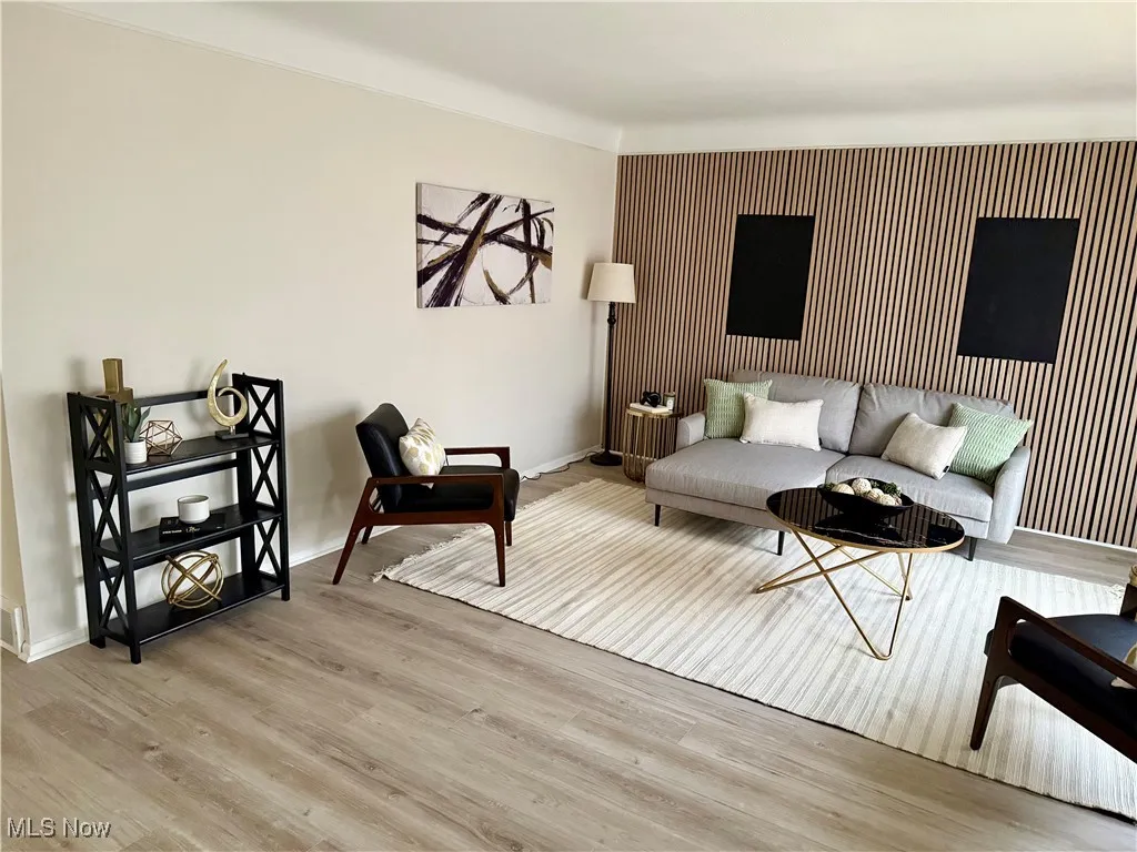 Living room featuring an accent wall and wood finished floors
