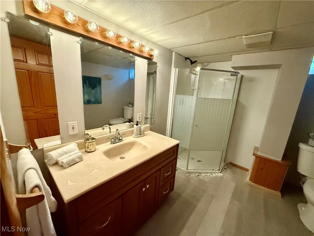 Full bath featuring a shower stall, vanity, and light wood-style flooring