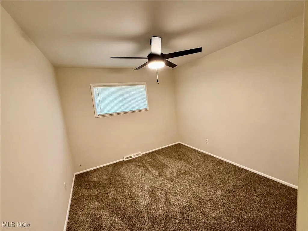 Spare room featuring carpet and a ceiling fan