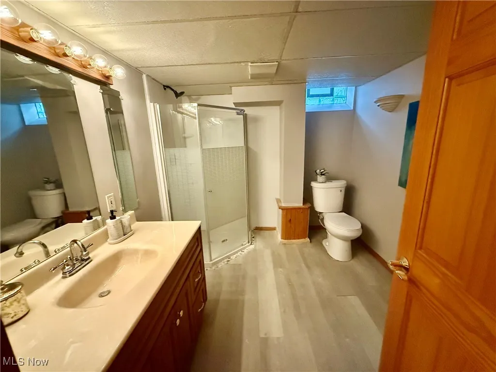 Bathroom featuring a stall shower, vanity, and light wood-style floors