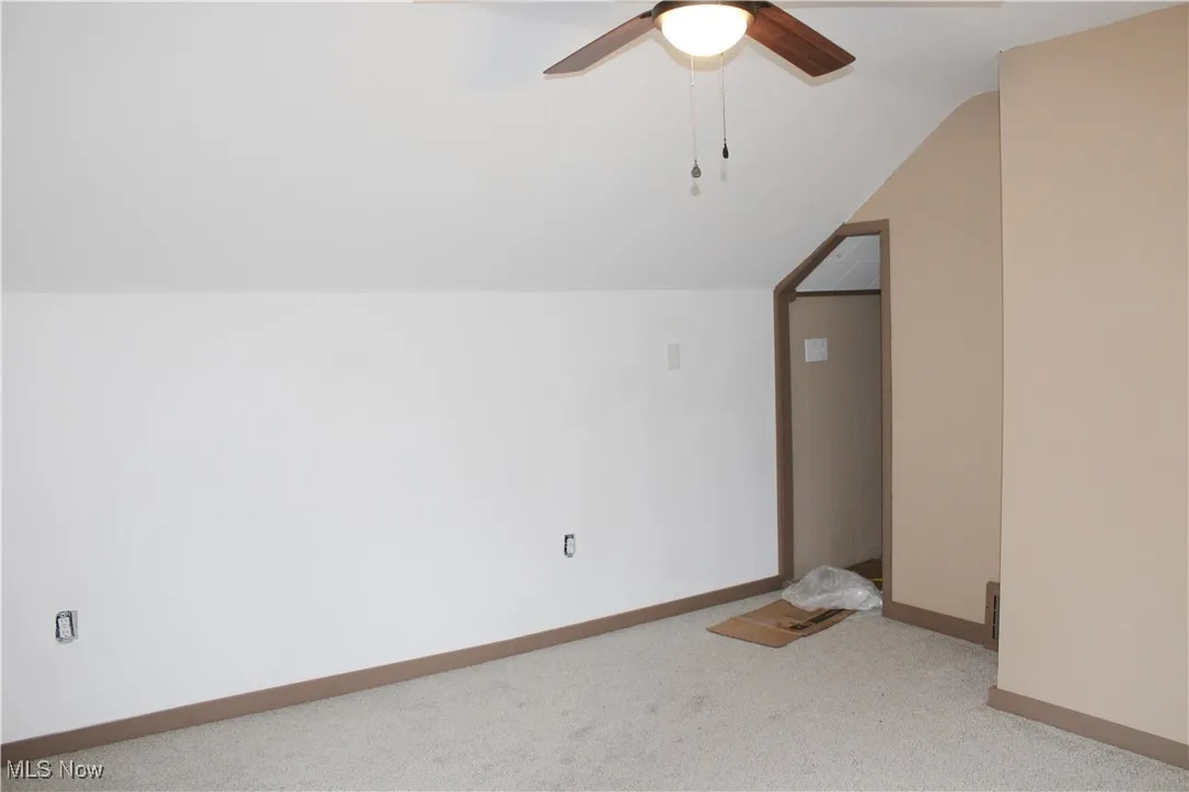 Additional living space with vaulted ceiling, carpet flooring, and a ceiling fan