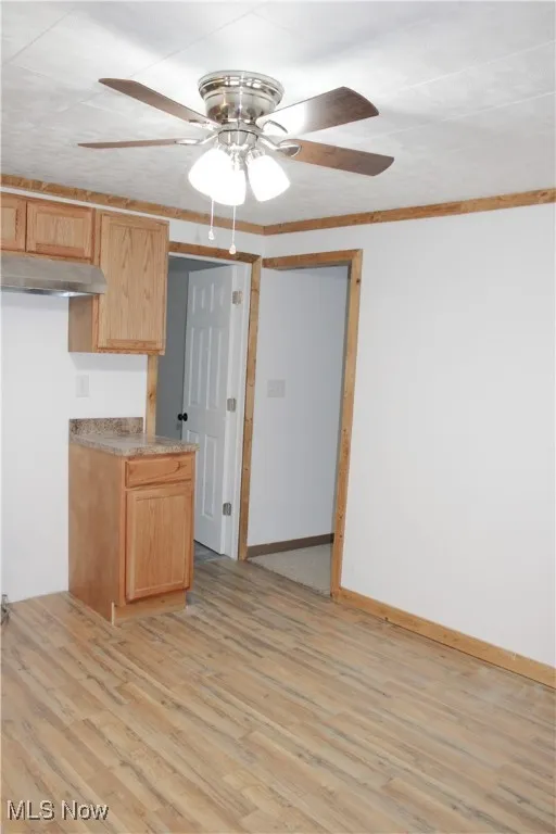 Kitchen with ceiling fan, light wood-style flooring, under cabinet range hood, and light brown cabinets