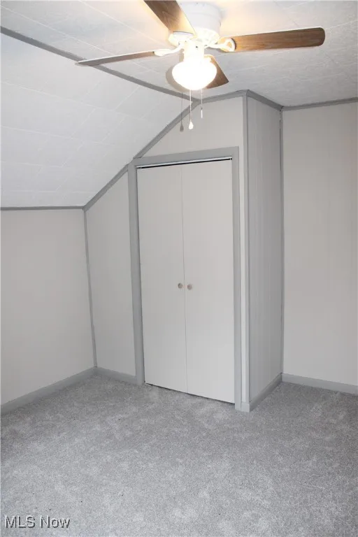 Additional living space with vaulted ceiling and light carpet