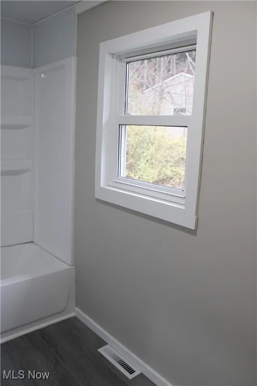 Full bath with dark wood-style flooring and shower / washtub combination