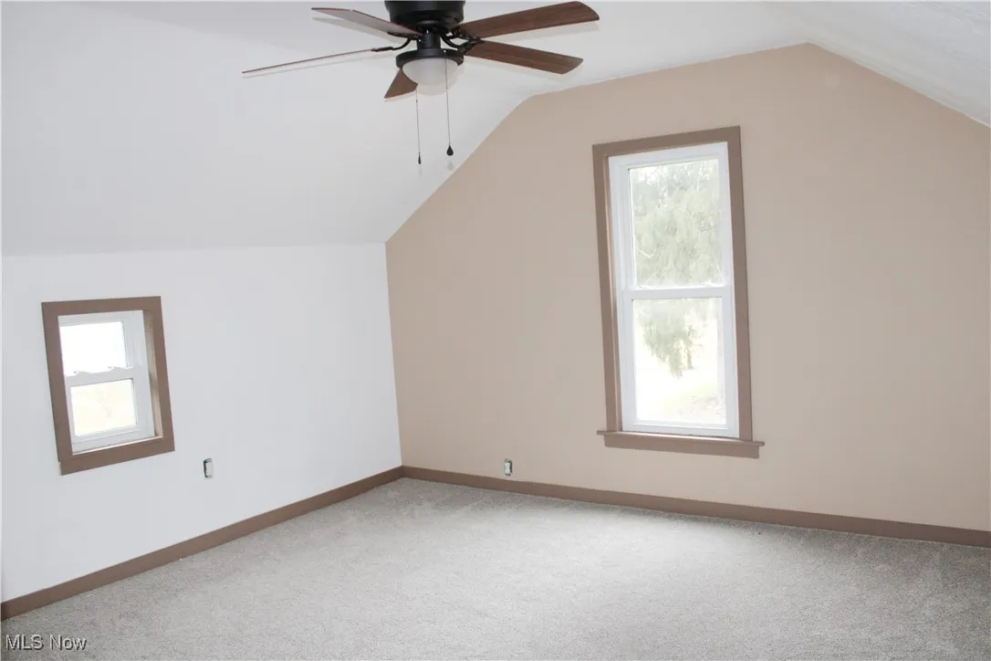 Additional living space featuring carpet, lofted ceiling, and ceiling fan