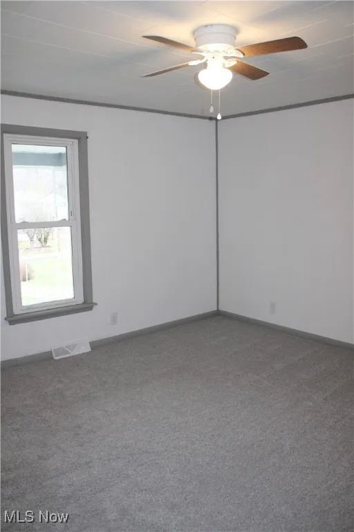 Empty room featuring carpet flooring and ceiling fan