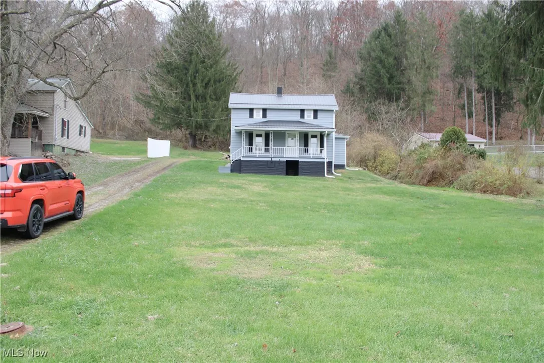 View of front of house with a metal roof, covered porch, and a front yard