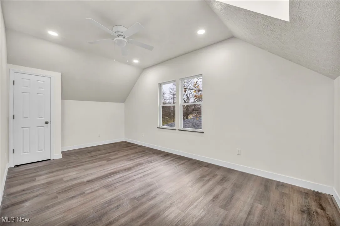 Additional living space with vaulted ceiling, light wood-style floors, ceiling fan, and recessed lighting