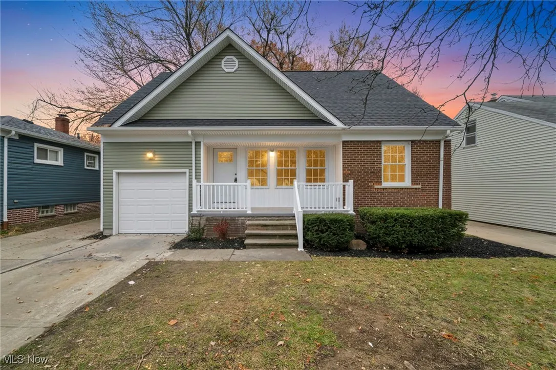 View of front of property featuring a porch, driveway, a shingled roof, a yard, and brick siding