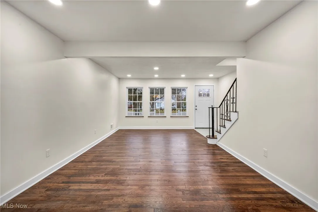 Unfurnished living room featuring stairs, recessed lighting, and dark wood-style floors