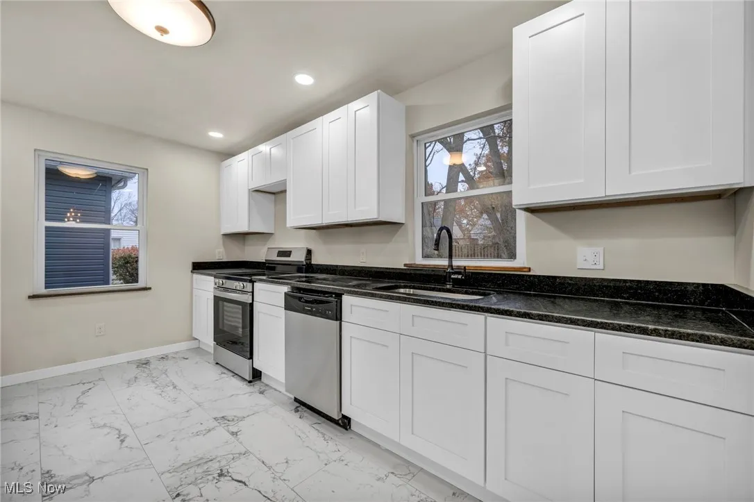 Kitchen featuring stainless steel appliances, plenty of natural light, light marble finish floors, white cabinets, and recessed lighting