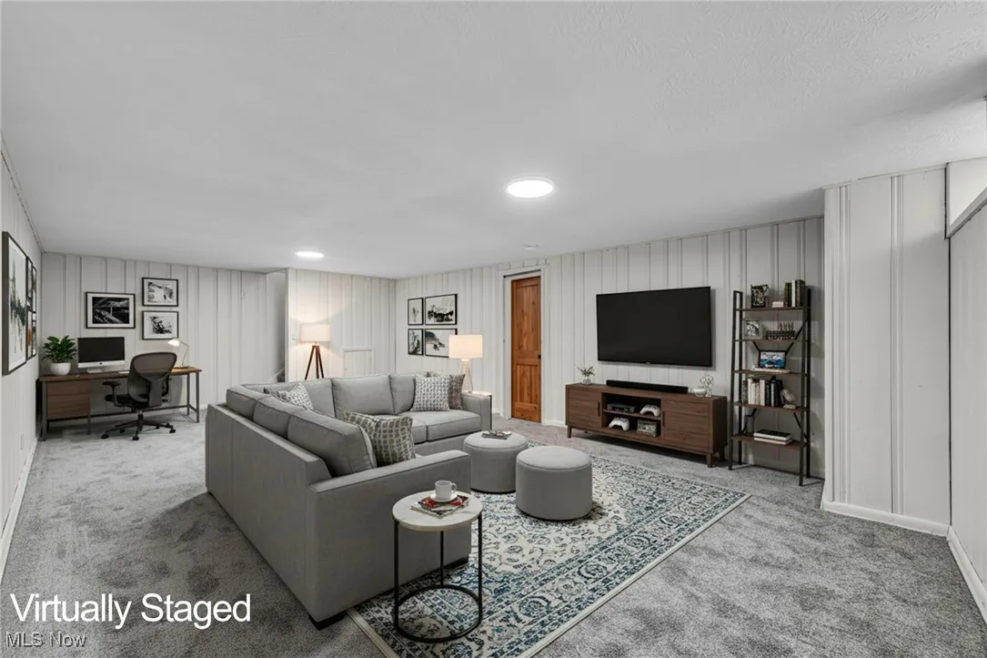 Carpeted living area featuring a desk and a decorative wall