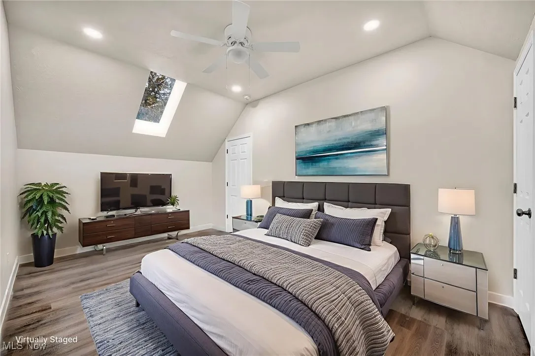 Bedroom featuring vaulted ceiling, a skylight, recessed lighting, wood finished floors, and a ceiling fan