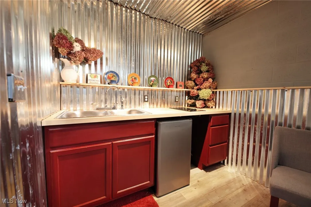 Bar featuring open shelves, light countertops, light wood finished floors, and dark brown cabinets