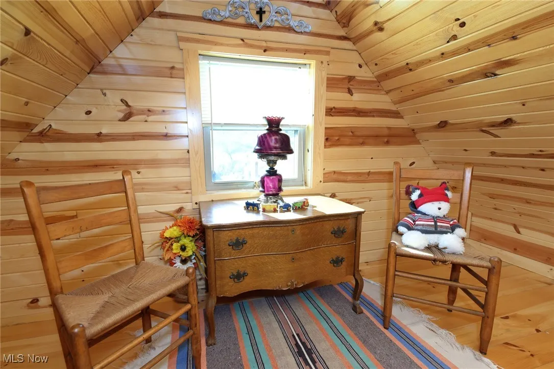 Living area with wooden walls, wood ceiling, wood finished floors, and vaulted ceiling