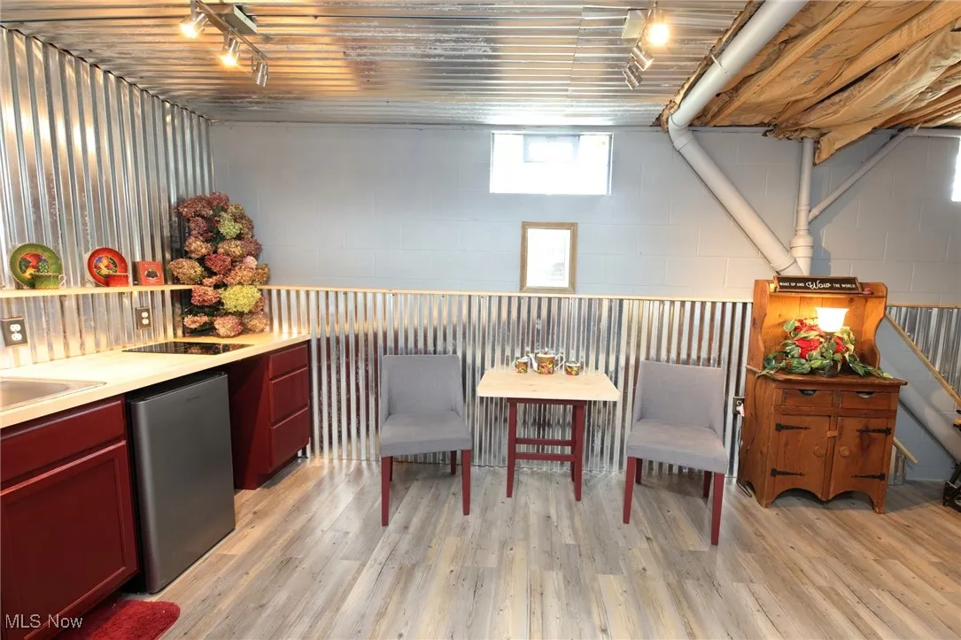 Bar area featuring light countertops, light wood-style flooring, stainless steel fridge, and reddish brown cabinets