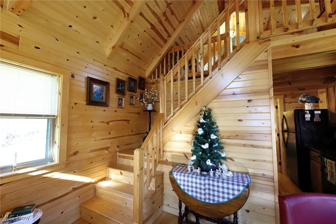 Stairs featuring wood walls, wooden ceiling, and lofted ceiling