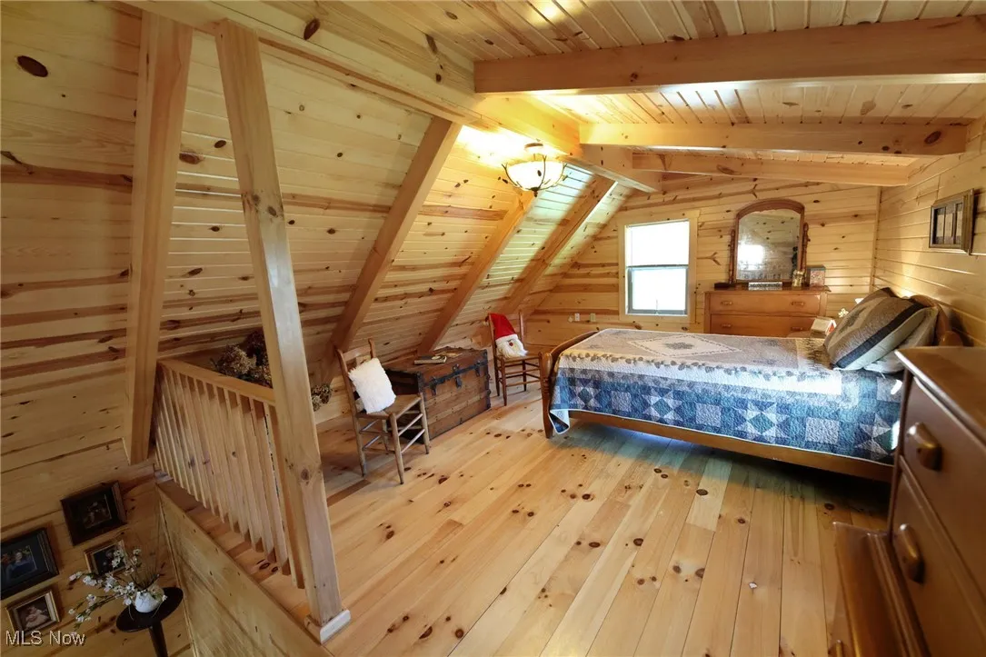 Bedroom with wood ceiling, wood walls, and light wood finished floors
