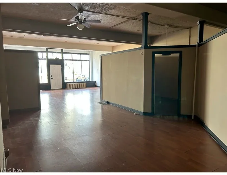 Spare room featuring radiator heating unit, ceiling fan, and dark wood-style flooring