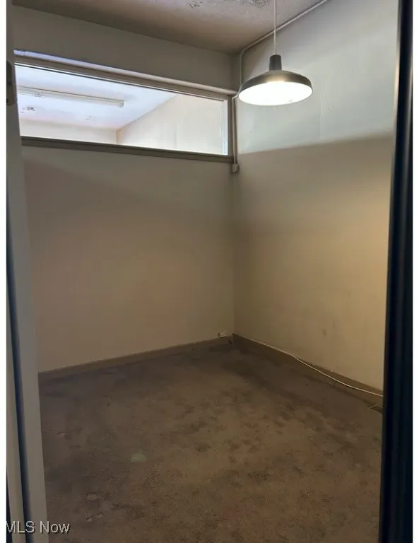 Empty room with dark carpet and a textured ceiling