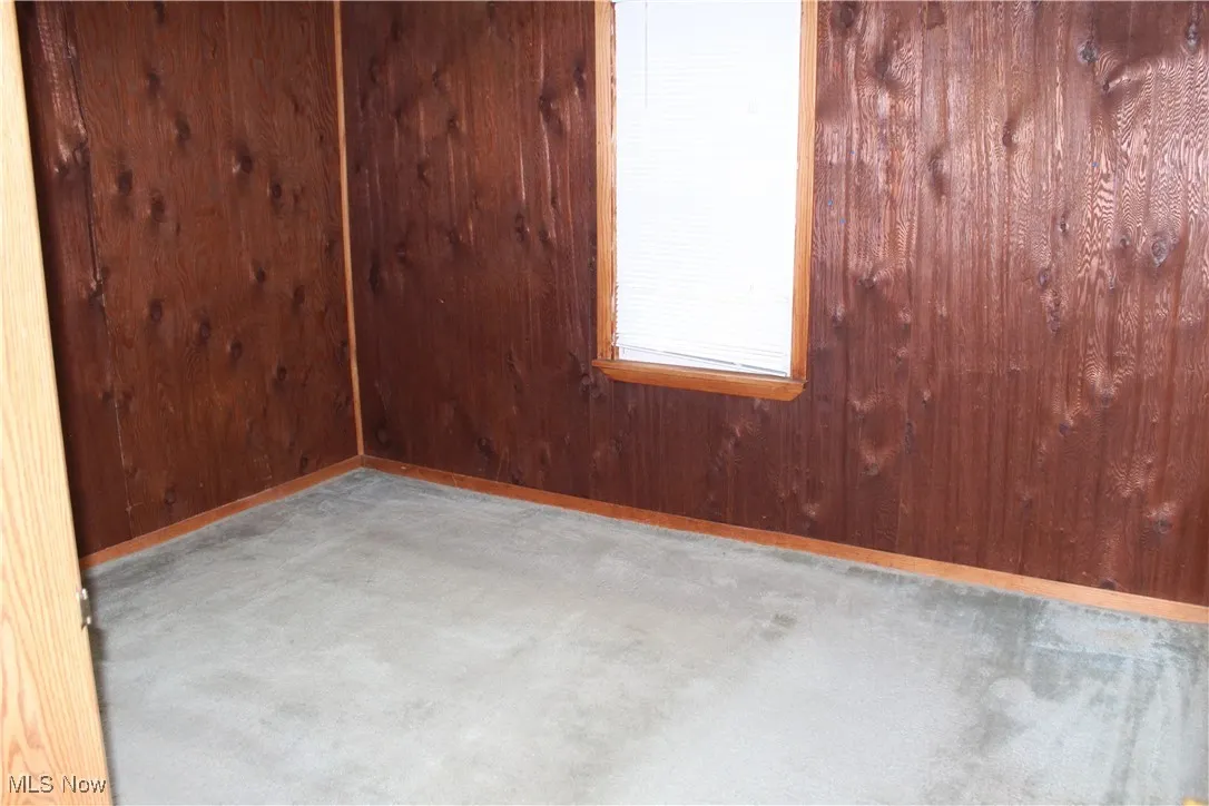 Spare room featuring wooden walls and concrete floors