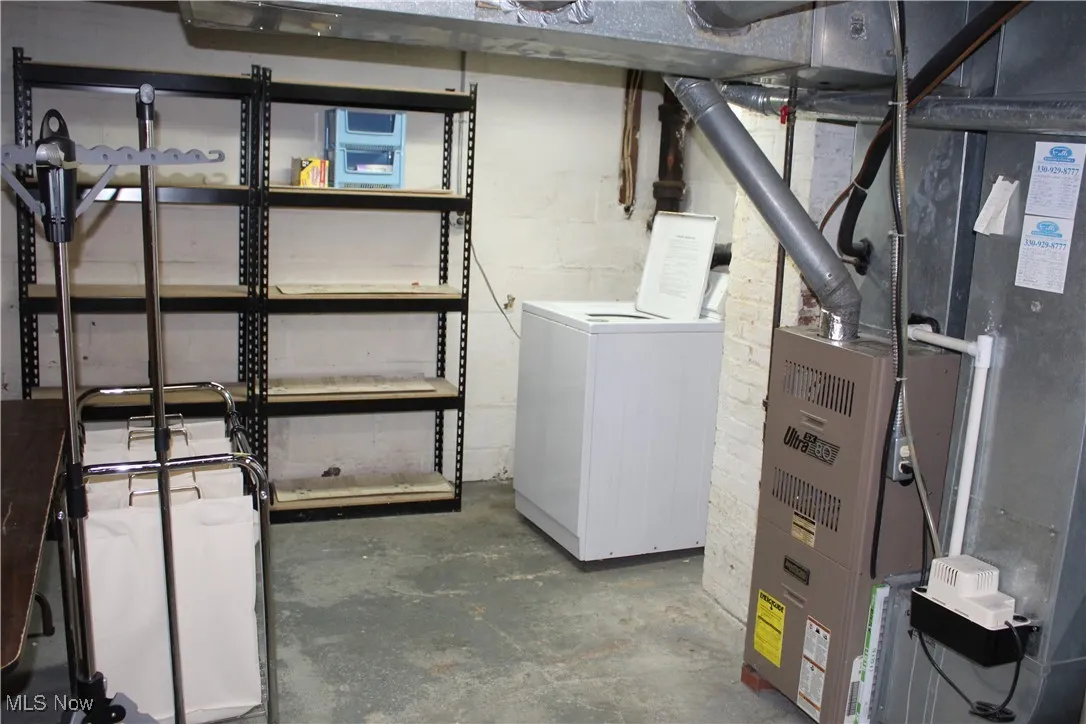 Unfinished basement with heating unit and washer / clothes dryer