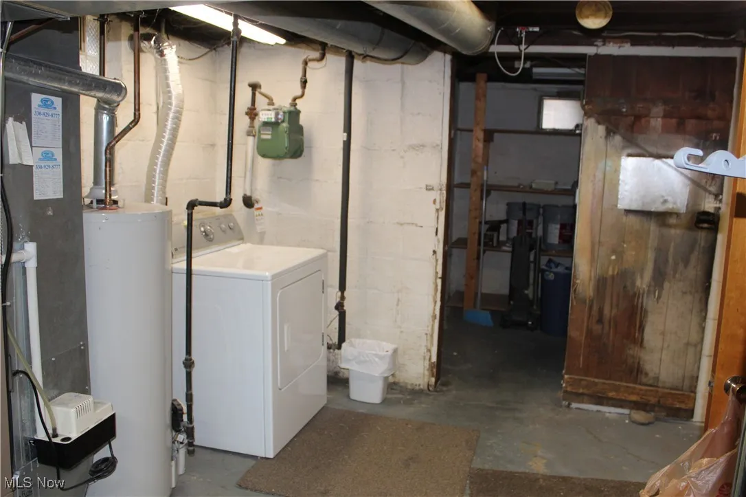 Unfinished basement featuring washer / dryer, water heater, and heating unit
