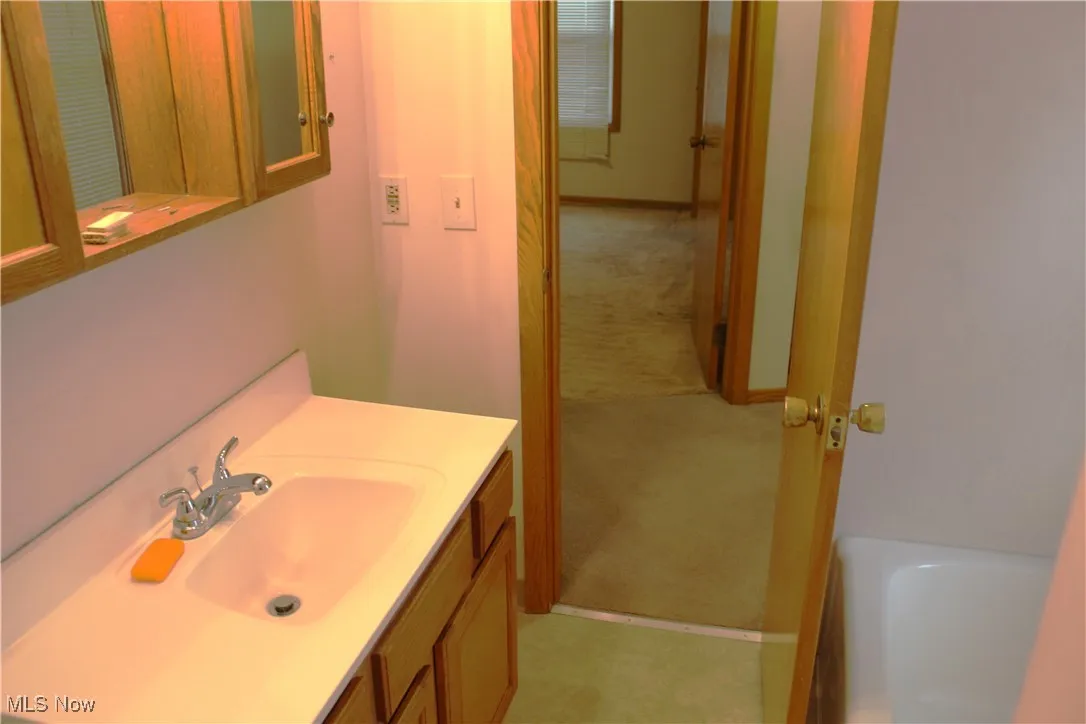 Full bath featuring light colored flooring, vanity, and a tub to relax in