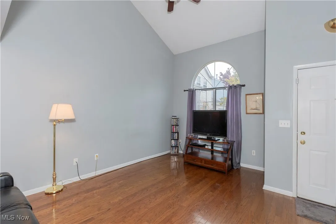 Living area featuring dark wood-style floors, high vaulted ceiling, and a ceiling fan