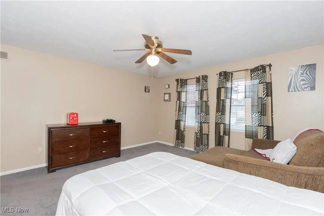 Bedroom with light carpet and a ceiling fan
