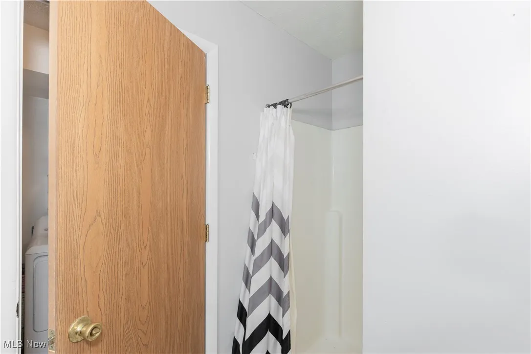 Bathroom featuring a shower with curtain and washer / dryer